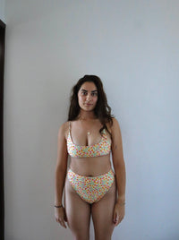 Enter the essence of coastal charm with our "Mabille" bikini. Designed with inspiration from tiny beach flowers found along the shores of Portugal, this buttery yellow bikini features intricate designs of small, colorful flowers. Embolizing the whimsical beauty of seaside blooms wherever your adventures take you. Perfect for beach swimwear and summer essentials.