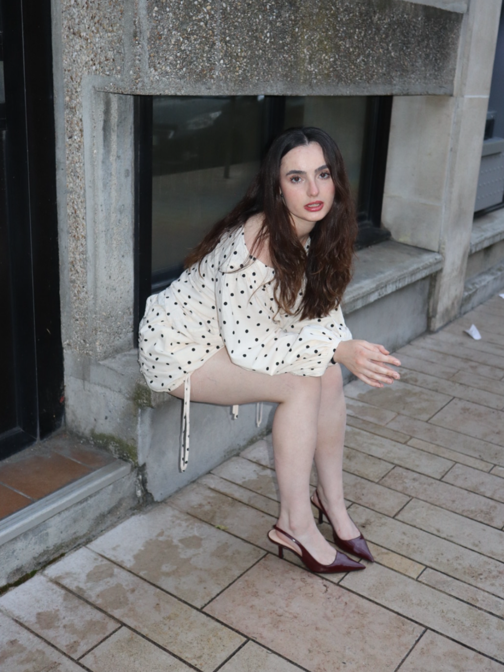 Woman in a polka dot dress sitting on a step outside a building