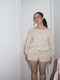 Woman wearing a polka dot outfit in front of a white door.